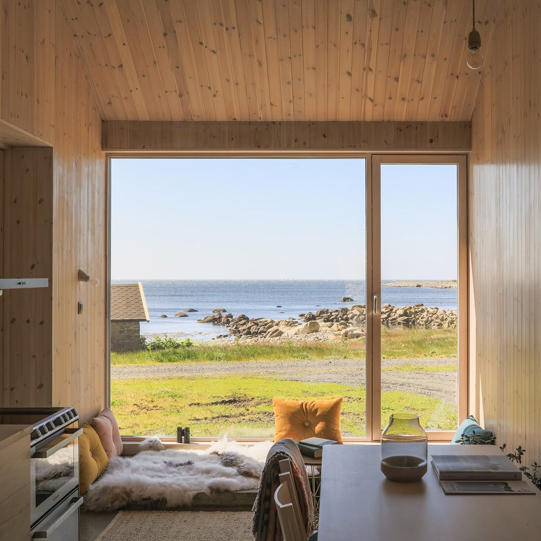 Bilde tatt fra innsiden av langhuset, med utsyn over fjæra og havet.