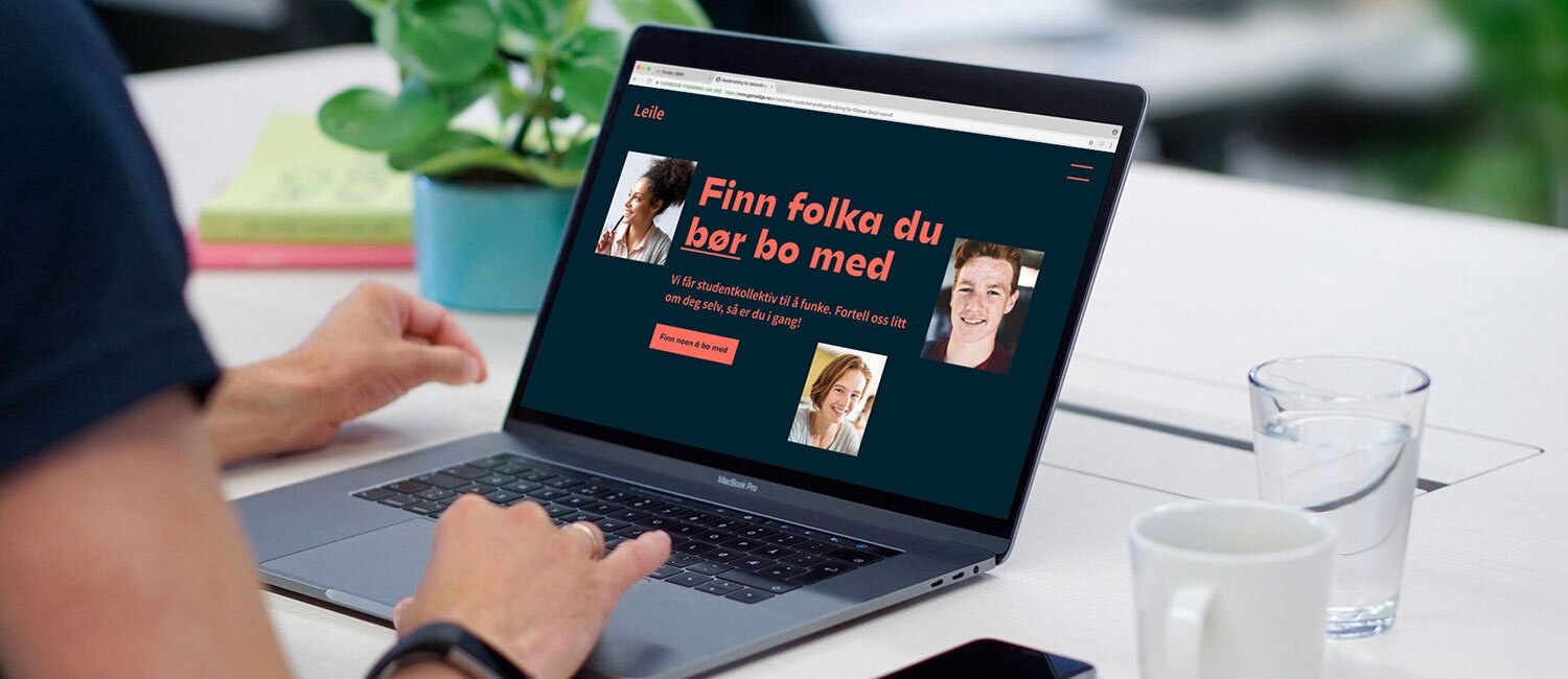 Bildet viser en person som sitter med en laptop med en side oppe hvor det står i rød skrift på mørk bakgrunn: "Finn folka du bør bo med".