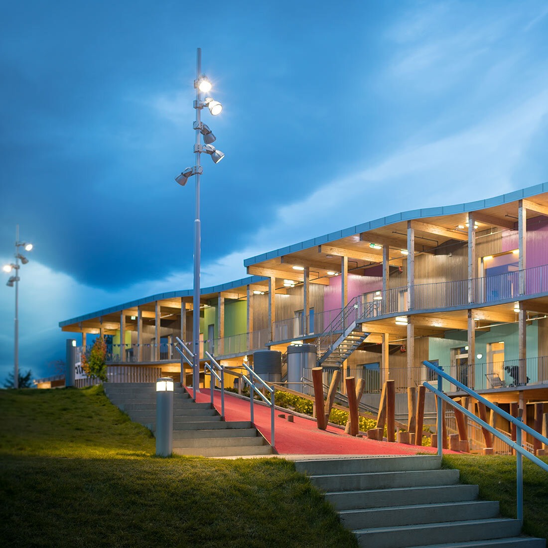 Et bygg ligger integrert i terreng, fra én til tre etasjer. Det har overbygde ytterganger og trepaneler vekselvis naturlig, og malt i klare pasteller. I forkant av bygget er en trapp, et lekeområde og en gressplen.