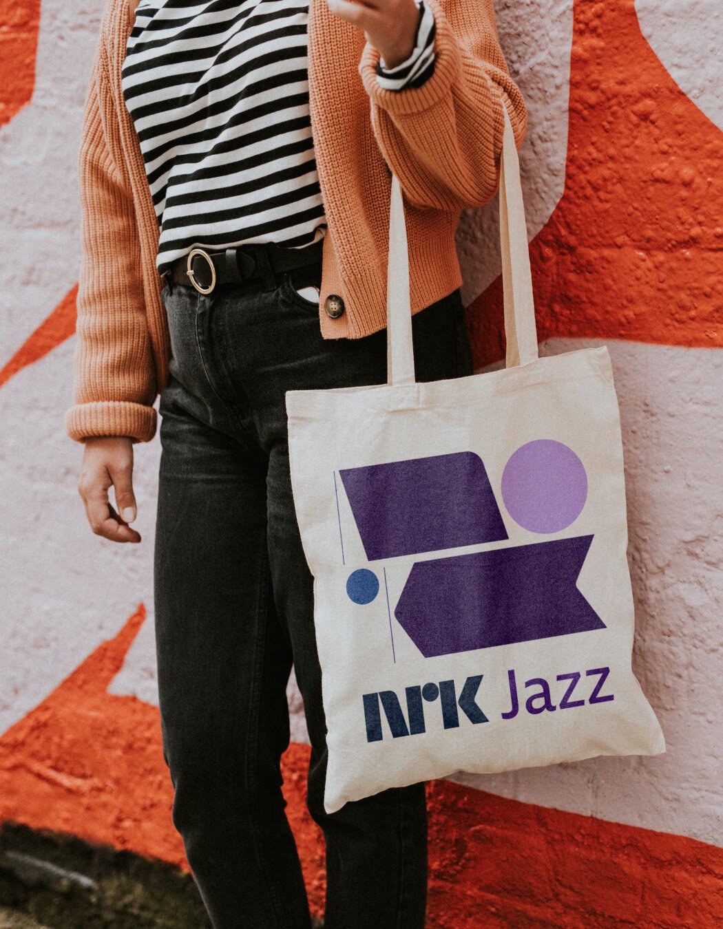 Nærbilde av en dame som holder en NRK-jazz totebag med lilla logo.