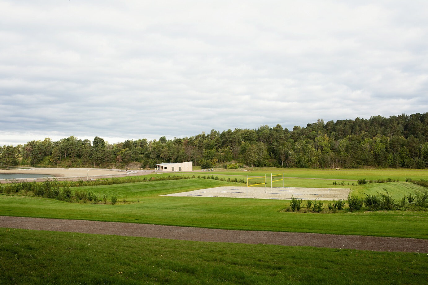 Stor gressslette i strandsonen med volleyballbane.