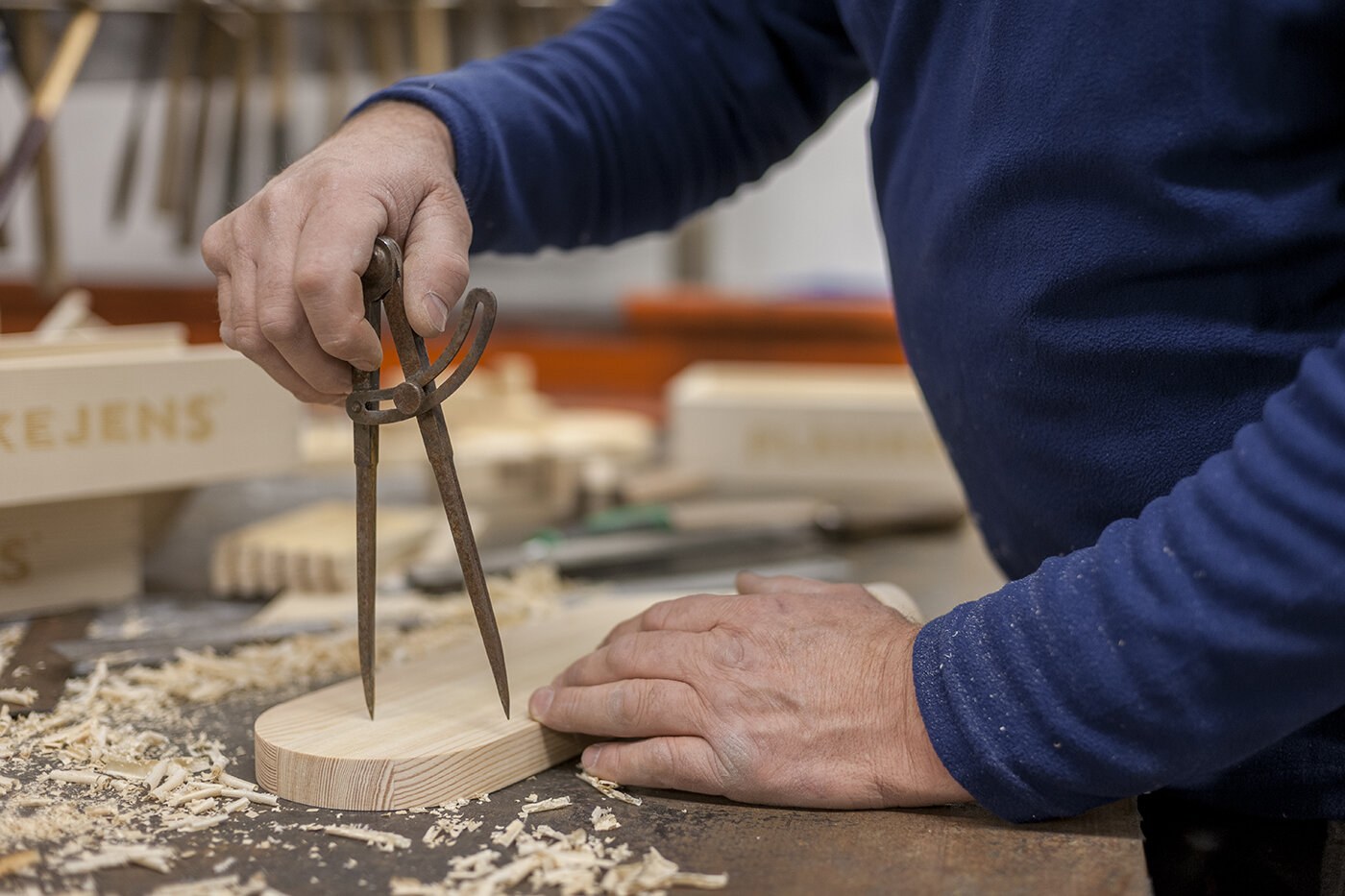 Et nærbilde av en mann som arbeider med et trestykke.