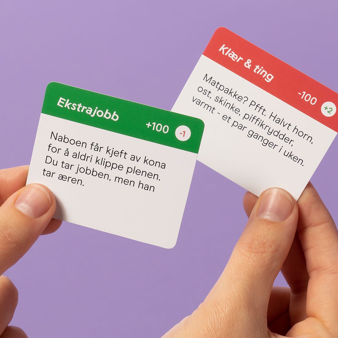To spillkort holdes opp: Et grønt: "Ekstrajobb (+100 kr): naboen får kjeft av kona for å aldri klippe plenen. Du tar jobben, men han tar æren." og "Klær og et rødt: "Klær og ting (-100kr): Matpakke Pfft. Halvt horn, ost, skinke, piffikryder, varmt – et par ganger i uken."