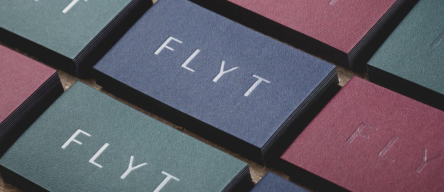 Bildet viser stabler med visittkort for Flyt, utført i matt farget papir i dempet blå, grønn og burgunder.