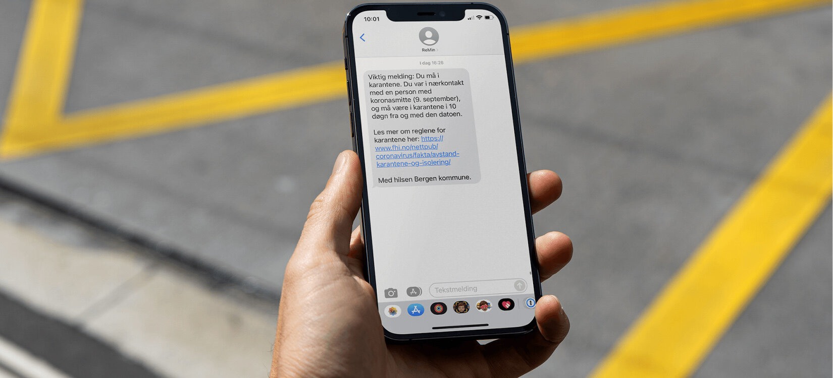 En hånd hoder en smarttelefon. På skjermen ses en ikke lesbar sms.