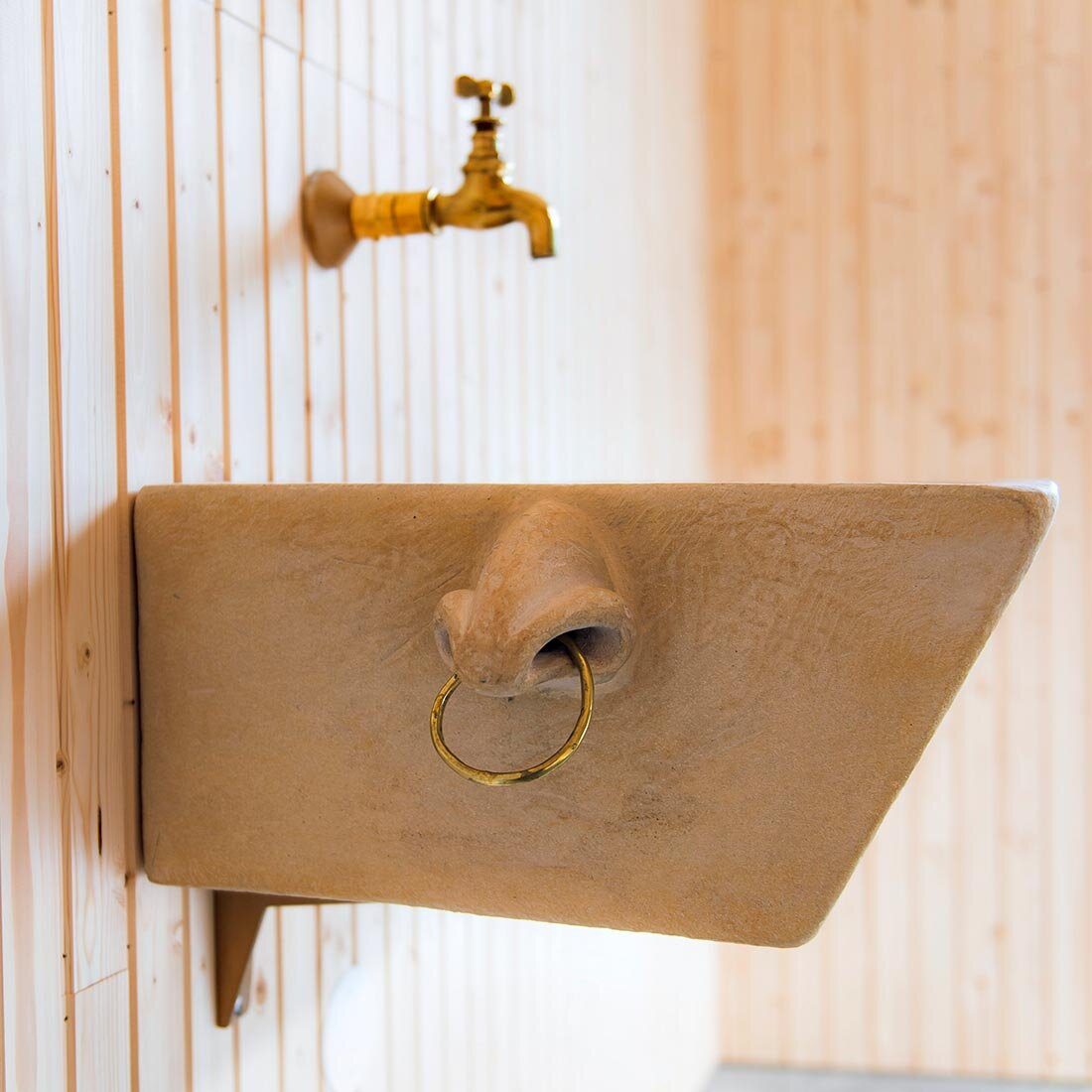 Nærbilde av siden av en servantskål hvor en stor nese med gullring er formet i leiren.