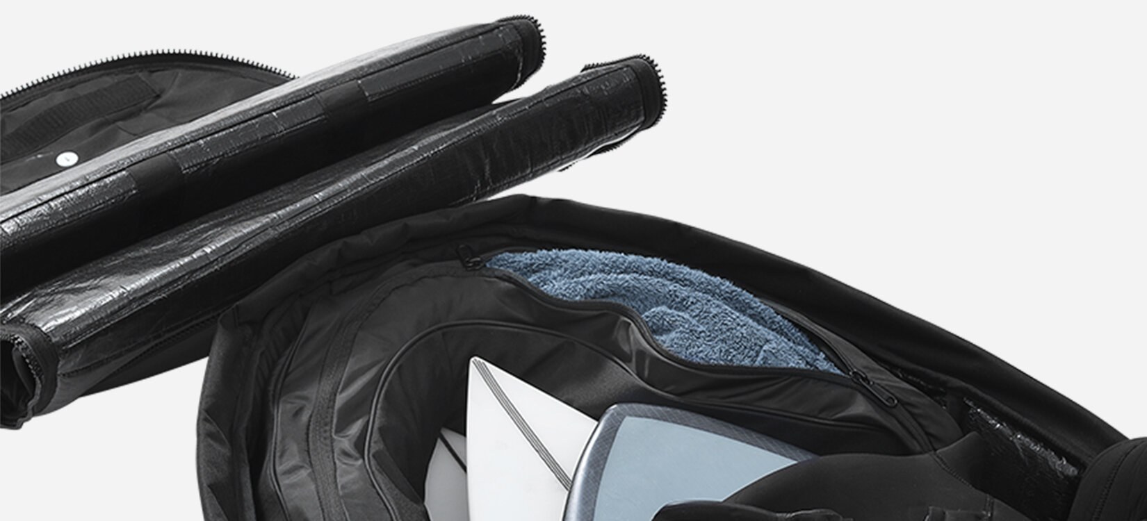 Nærbilde av en bag med surfebrett oppi. En halvveis lukket glidelås avslører at det er brukt håndkler som polstring rundt tuppen av brettene.