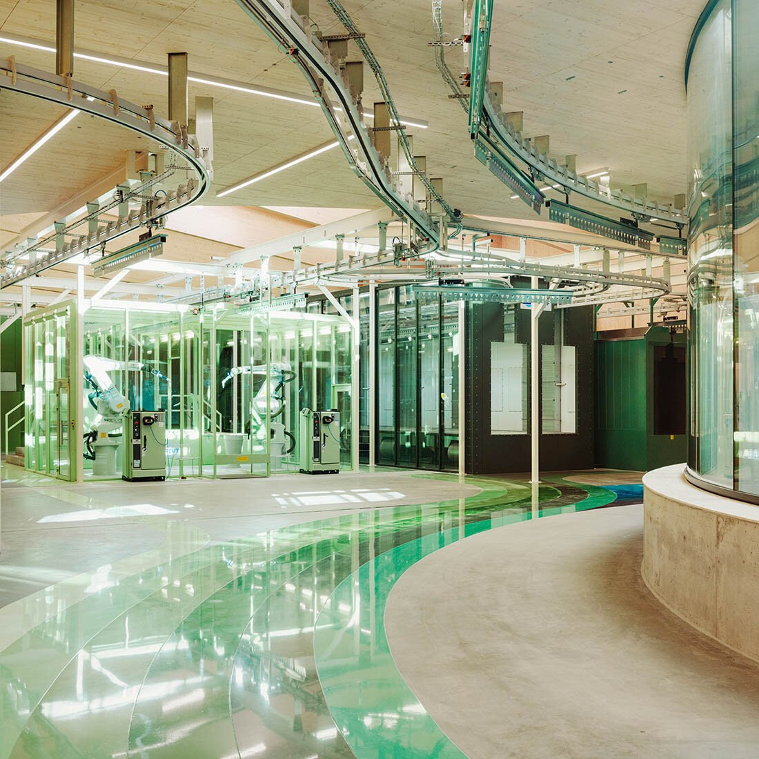 Moderne produksjonslokaler, med tekniske installasjoner, samt grønnfarge i gulvet som viser vei mot en dør.