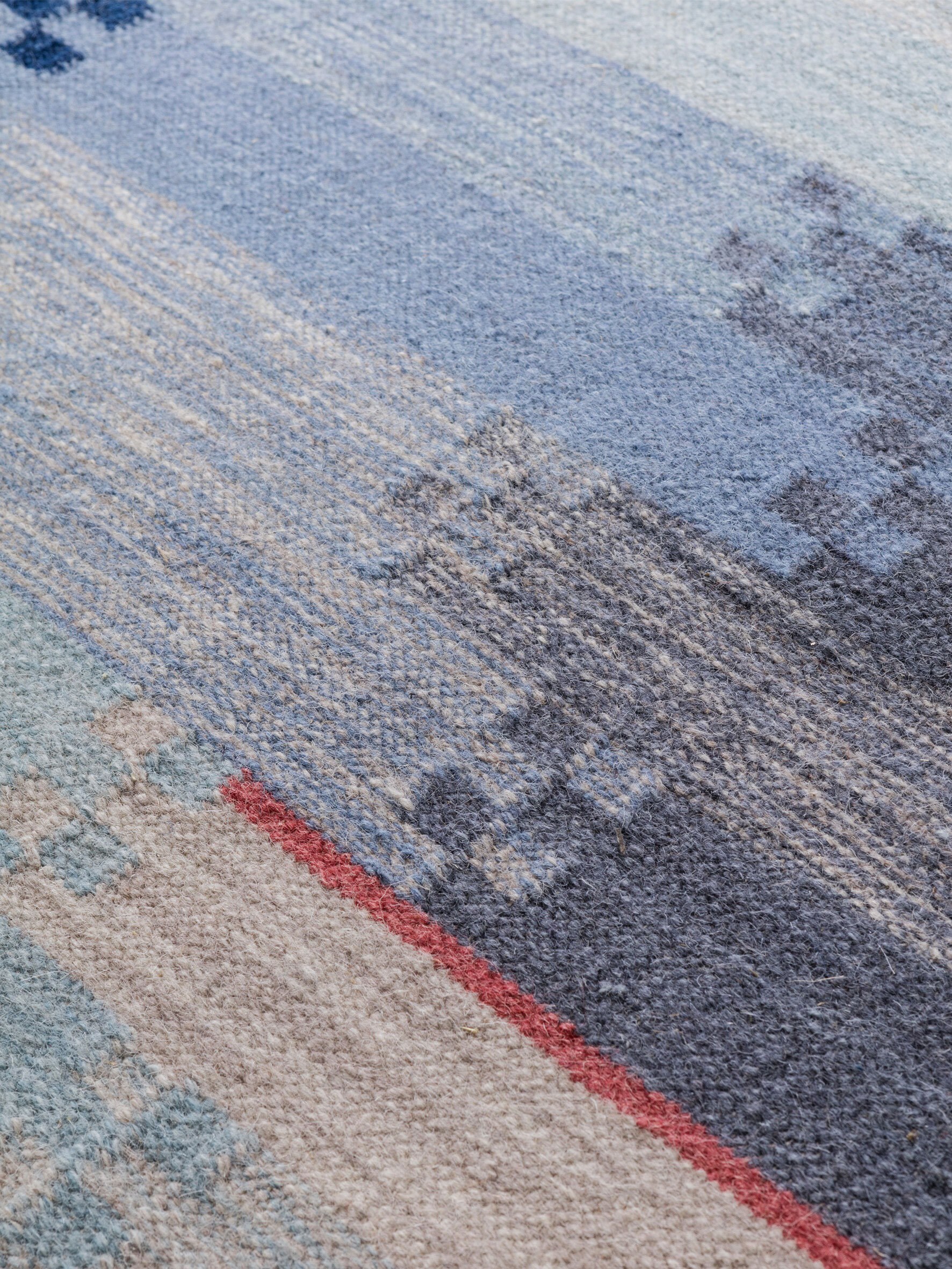 Detaljfoto av et vevet teppe i nyanser av blått