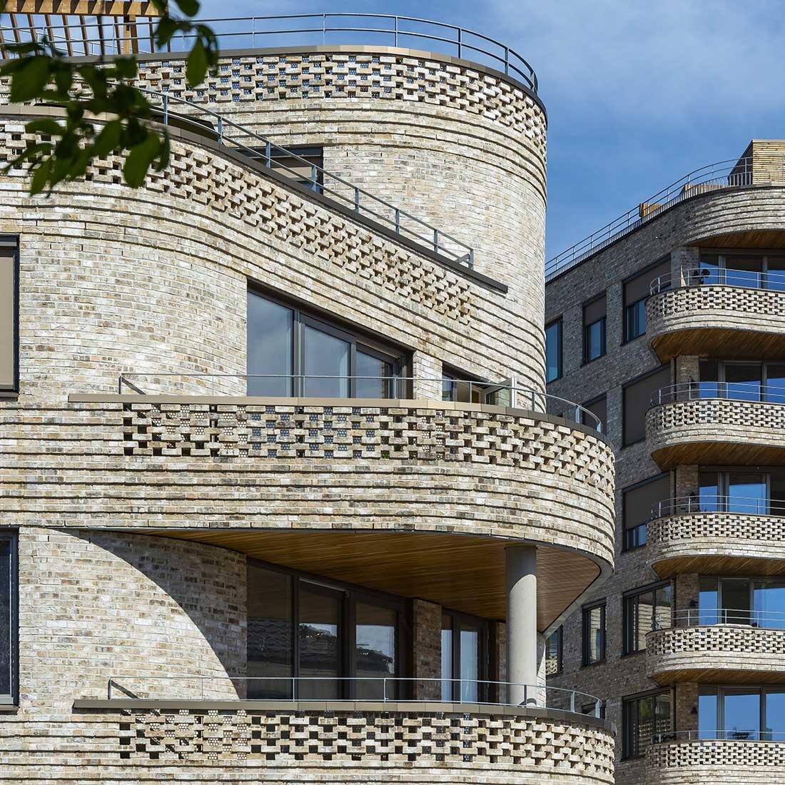 Foto av detaljering i Wesselkvartalets fasade. Rundt balkonger er murstein lagt i et mønster som gir variasjon og lysinnslipp.