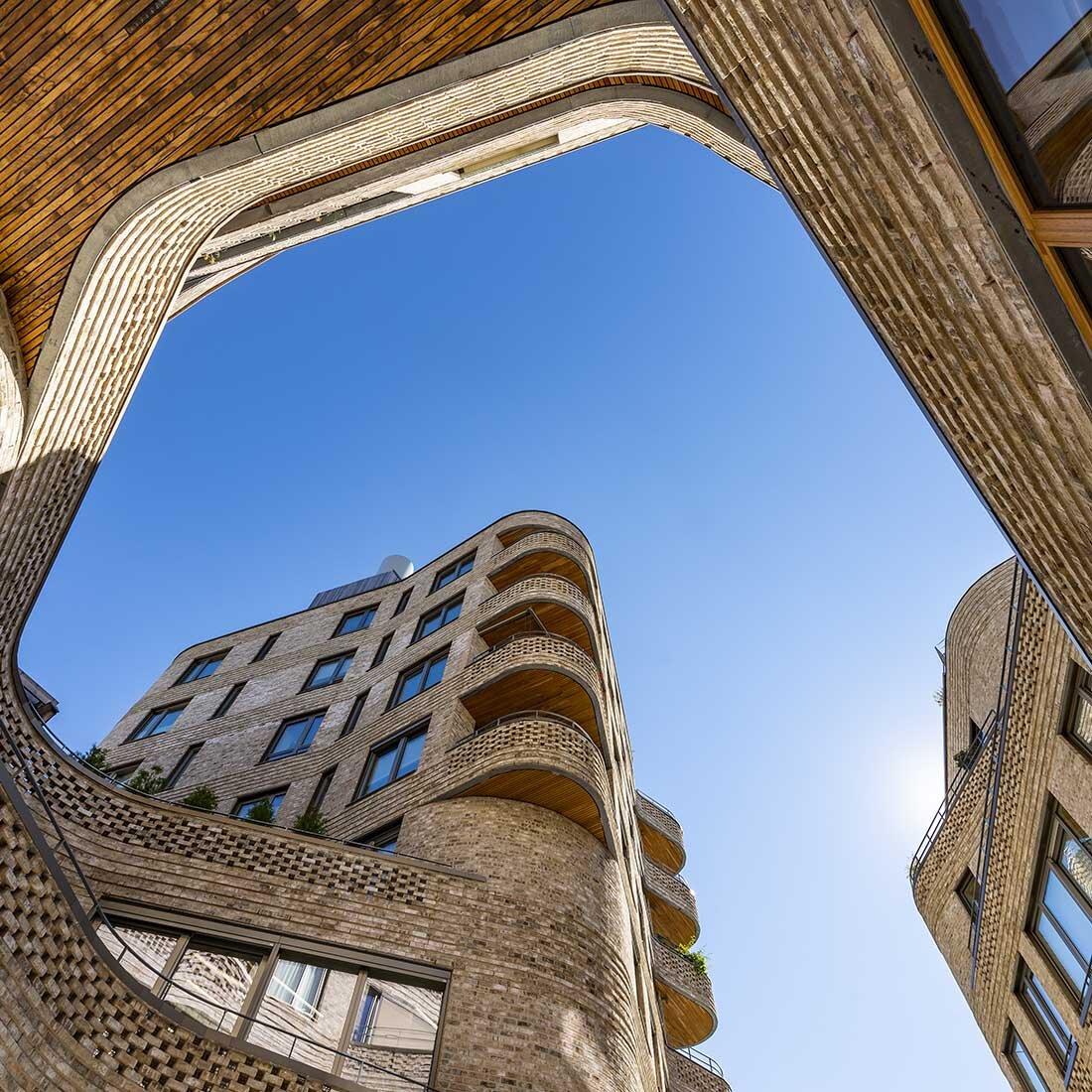 Foto som viser Wesselkvartalet fra bakken og fasaden i lys tegl som strekker seg mot klar, blå himmel.