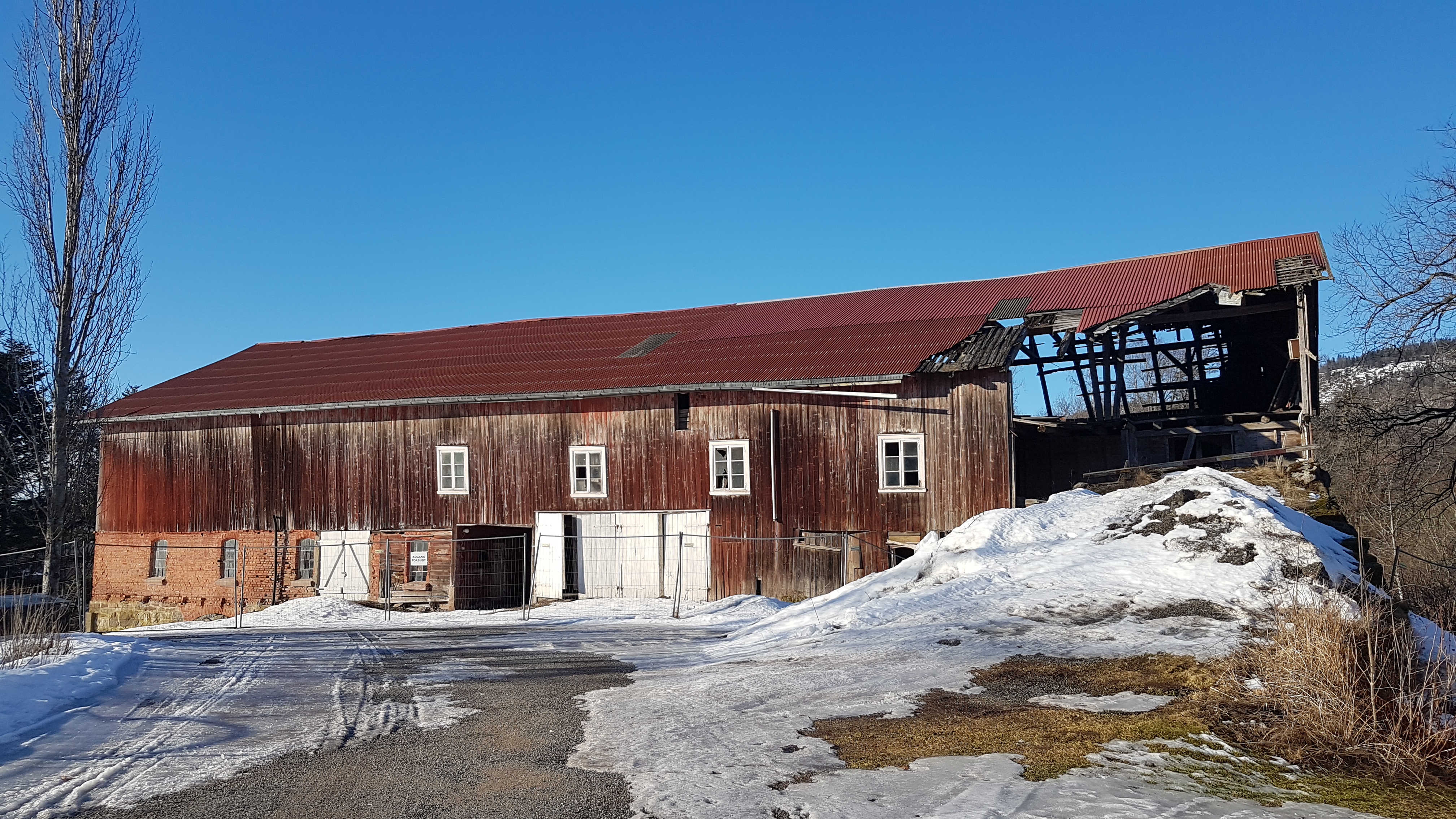 En falleferdig låve med smeltende snø utenfor.