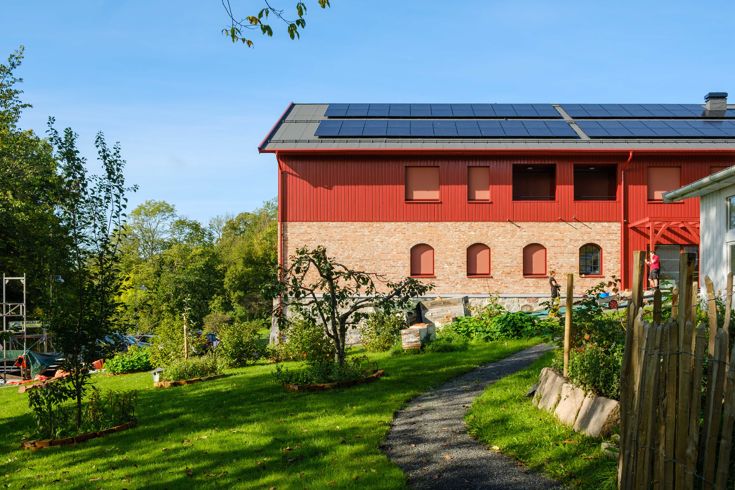 Foto av en stor modernisert låve med en hage utenfor.