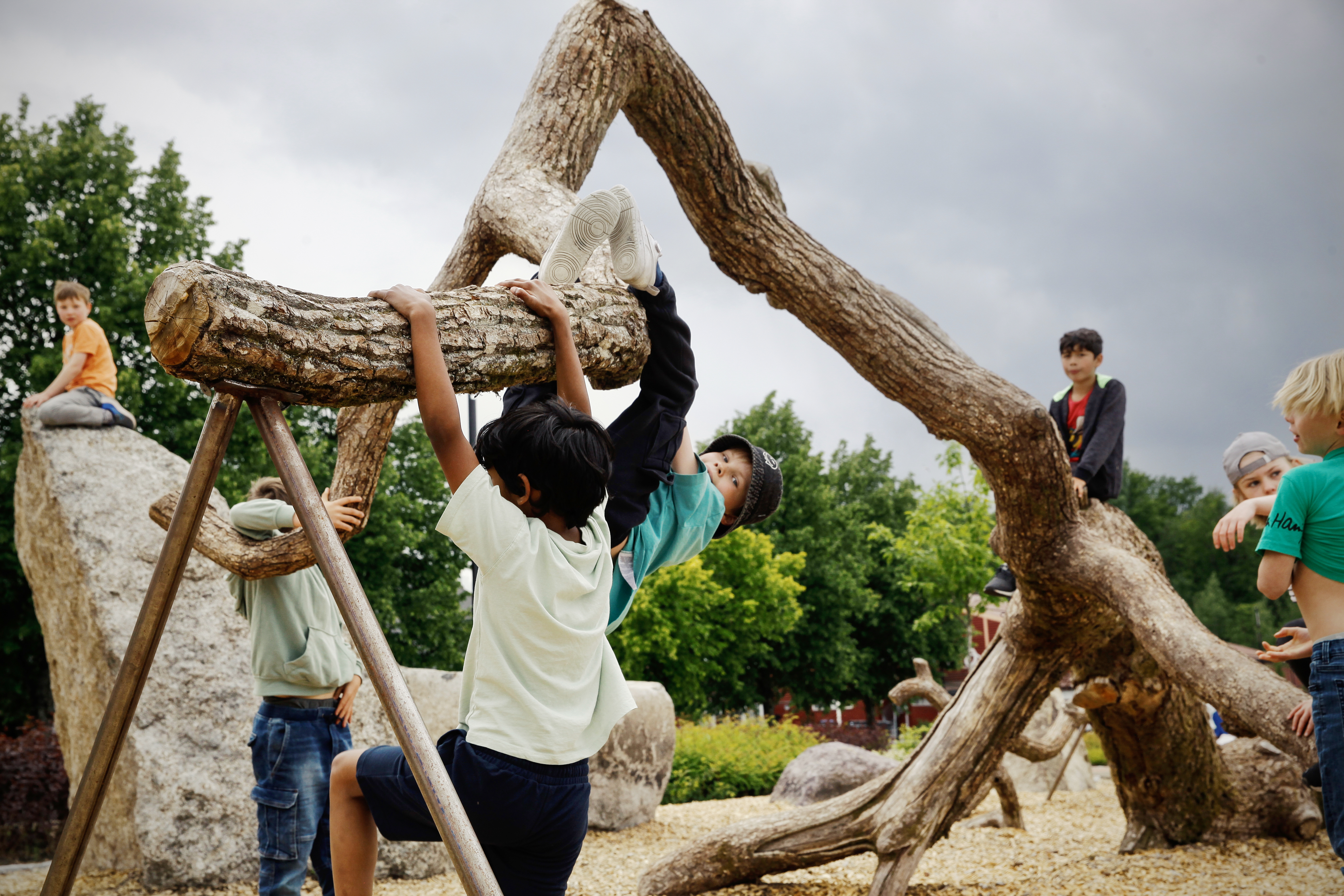 Foto av barn som klatrer i et lekestativ laget av gamle trær.