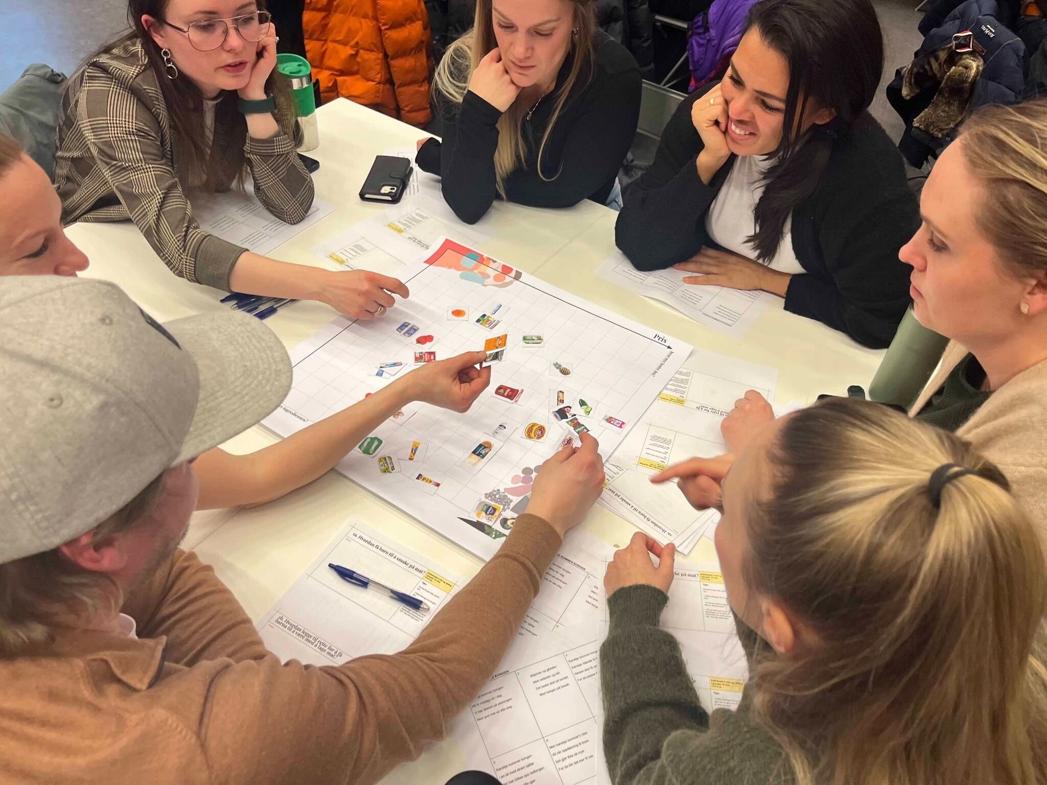 Mange kvinner rundt et bord som alle deltar engasjert i en workshop.