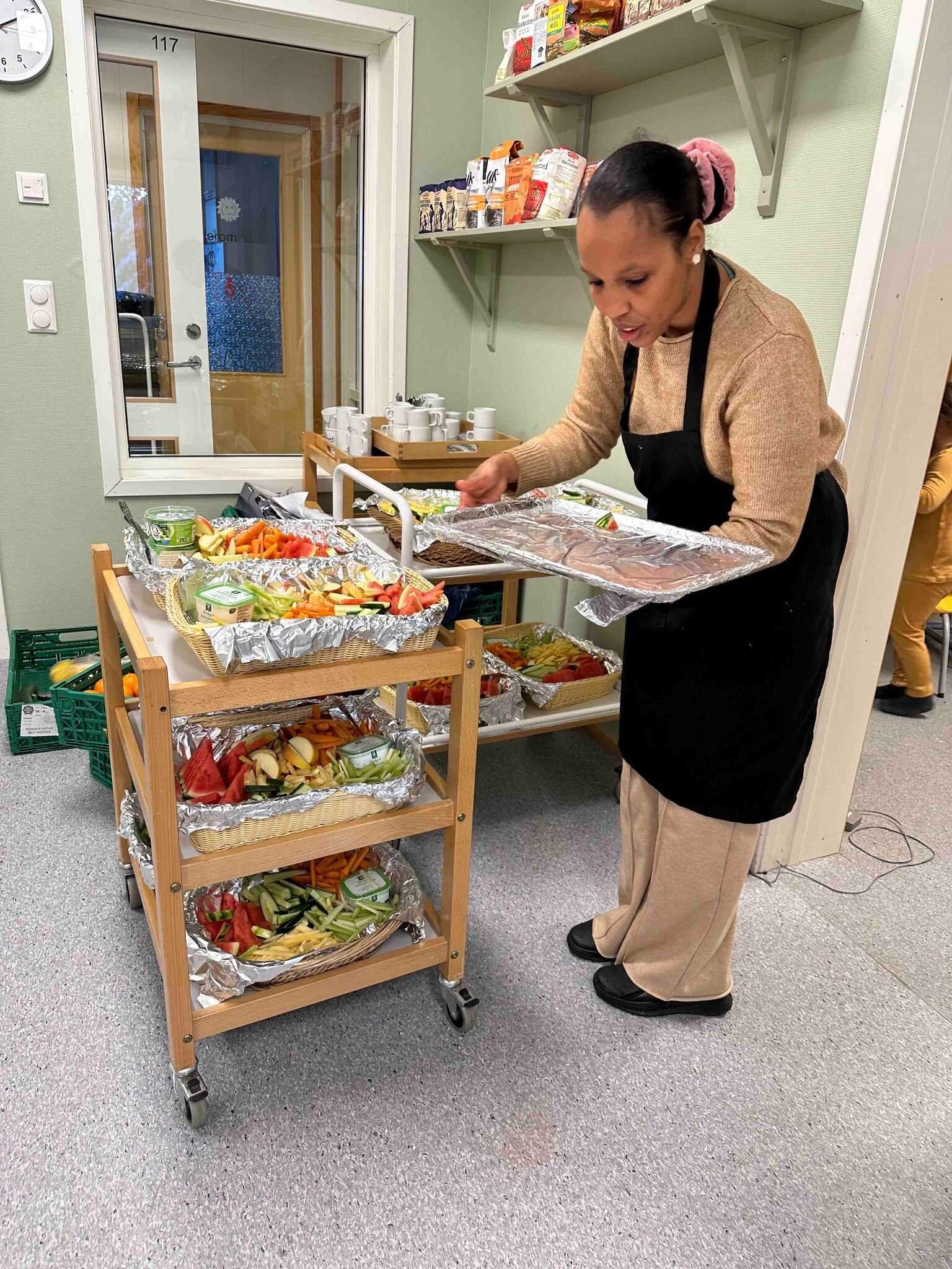 En kvinne står ved et trillebord fullt av mat.