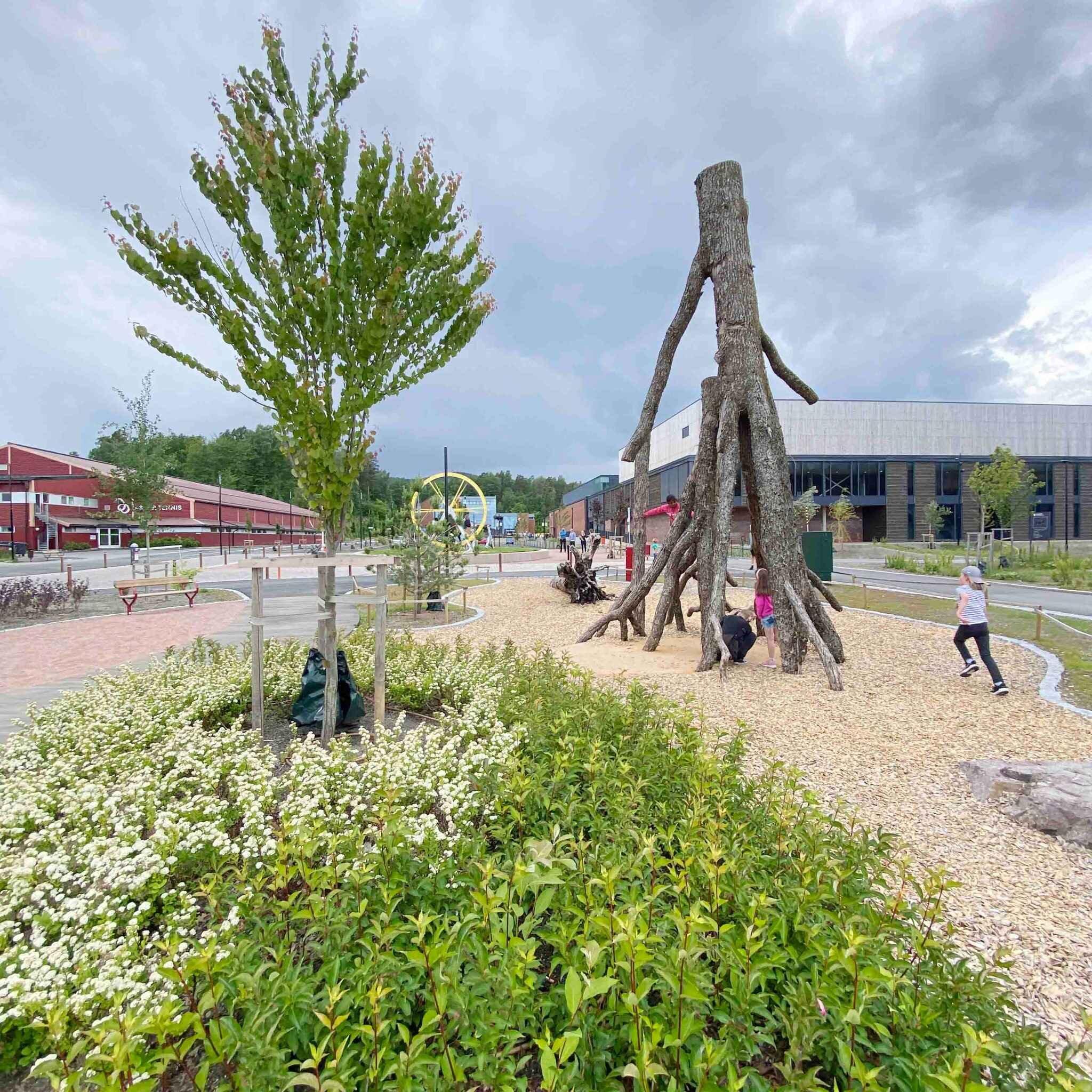 En stor trestamme med grener plassert opp ned på en lekeplass.