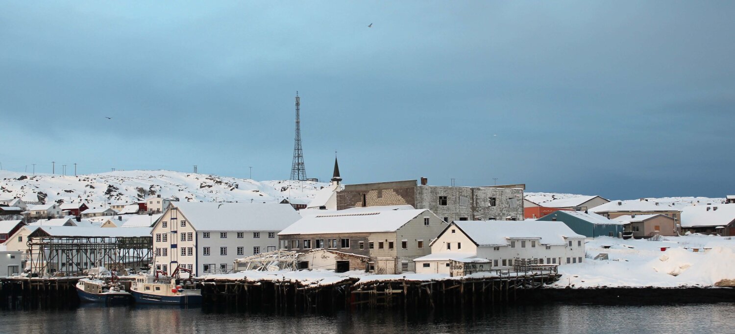 Oversiktsbilde over bebyggelse rundt et fiskevær, sett fra sjøen.