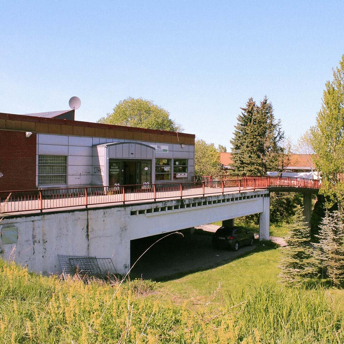 Fotografi av et forfallent lokalsenter omgitt av frodig natur.