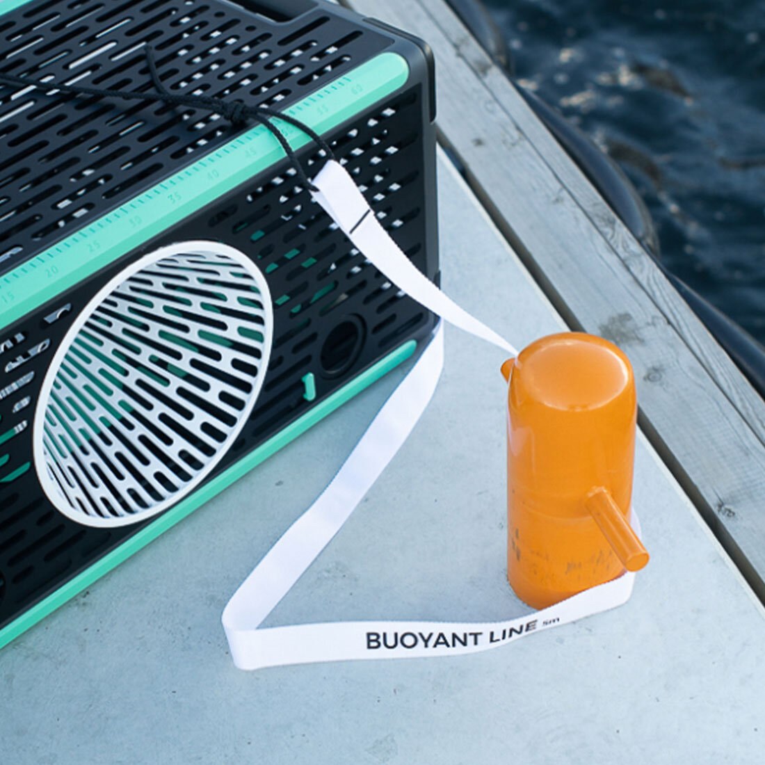 Detaljbilde av teinen på bryggekanten, med en stropp rundt et oransje forankringspunkt.