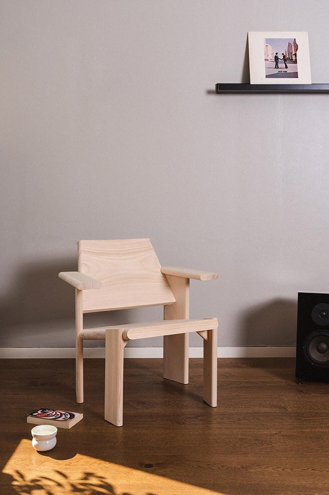 En ubehandlet trestol står på gulvet mot en gråmalt vegg.