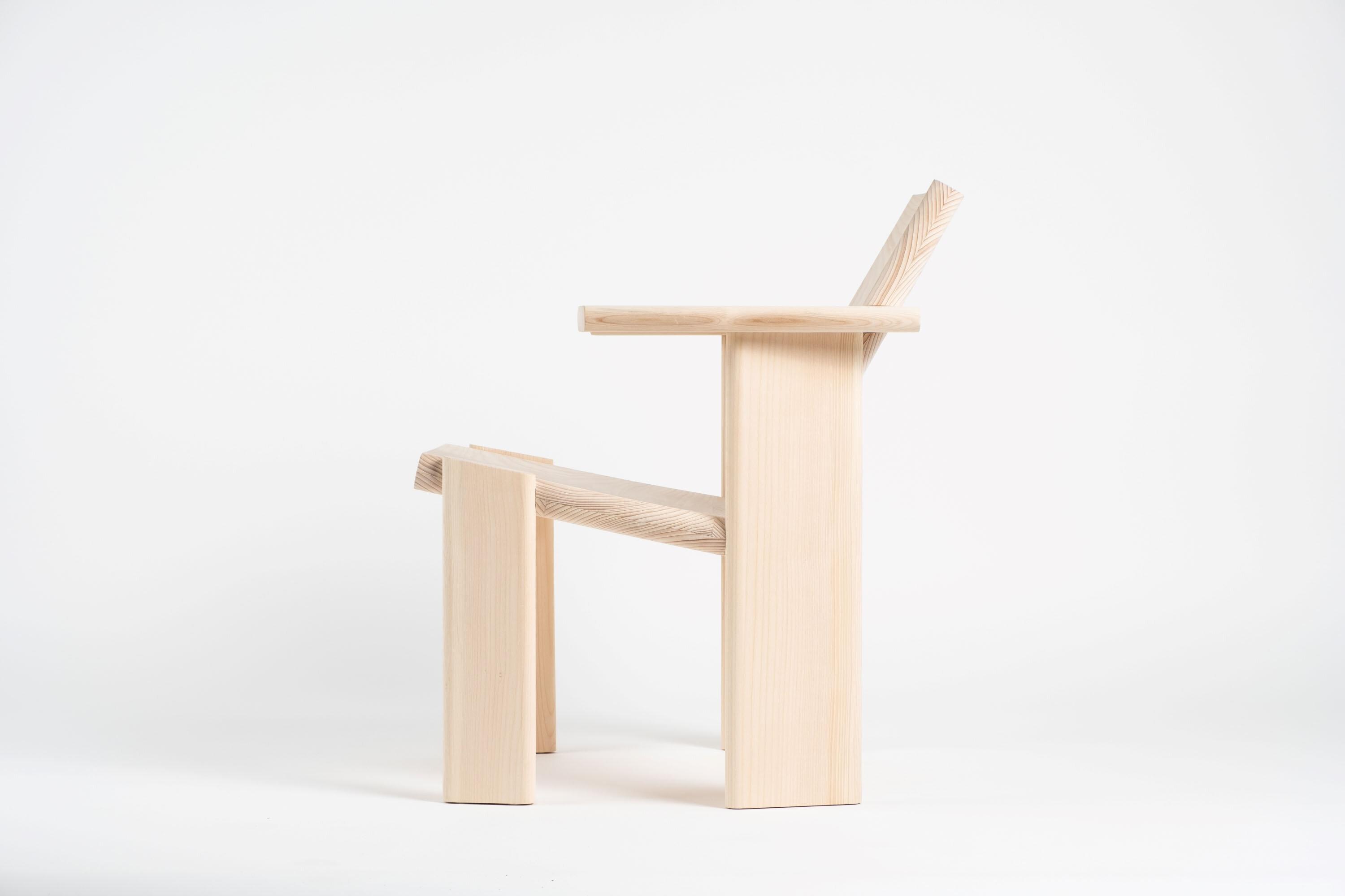 En liten lenestol i ubehandlet tre, sett fra siden mot en hvit bakgrunn.