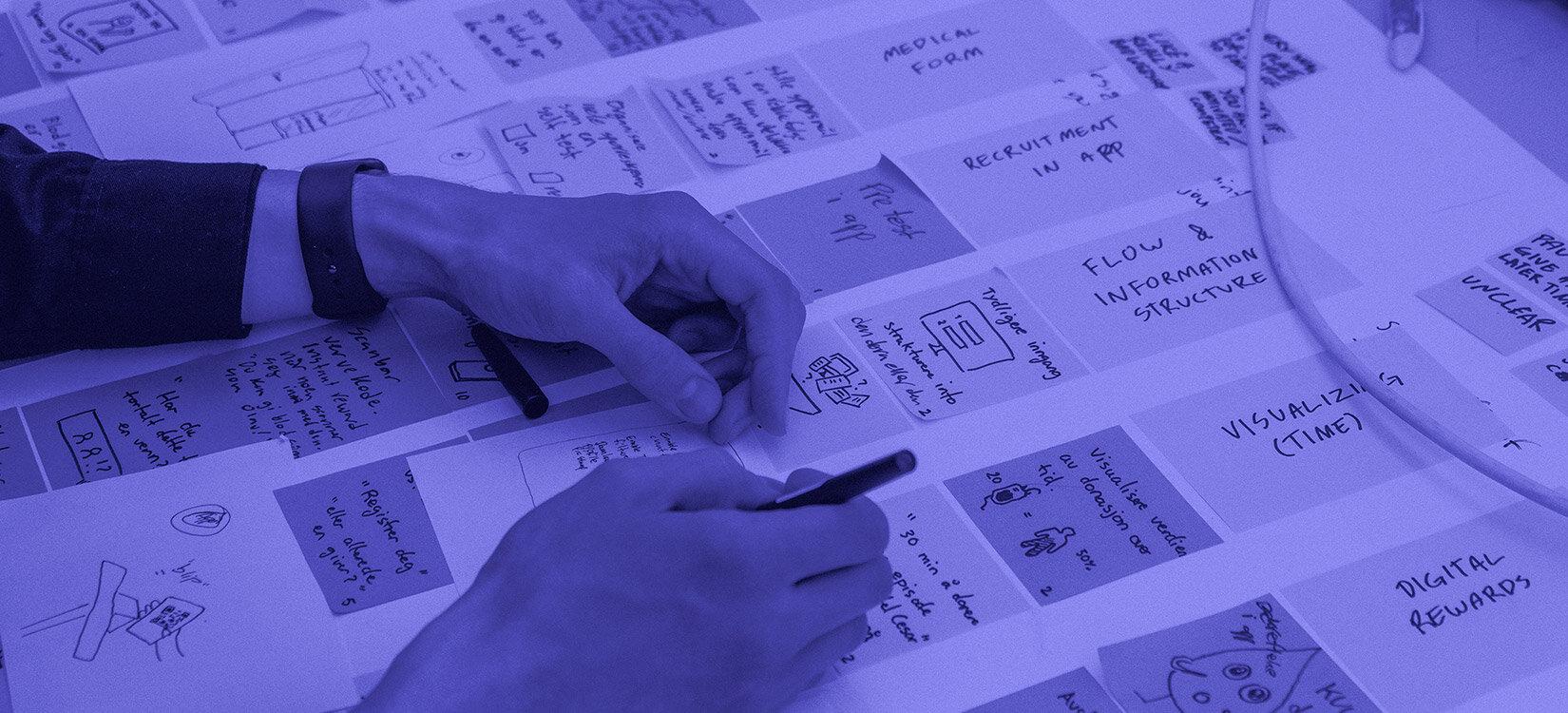 Nærbilde av to hender som noterer på en plansje