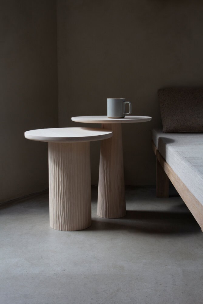 Bordet Pedestal i et minimalistisk inetiør, i to ulike høyder. Ett med smalende base mot den runde bordplaten – den andre med rett form.