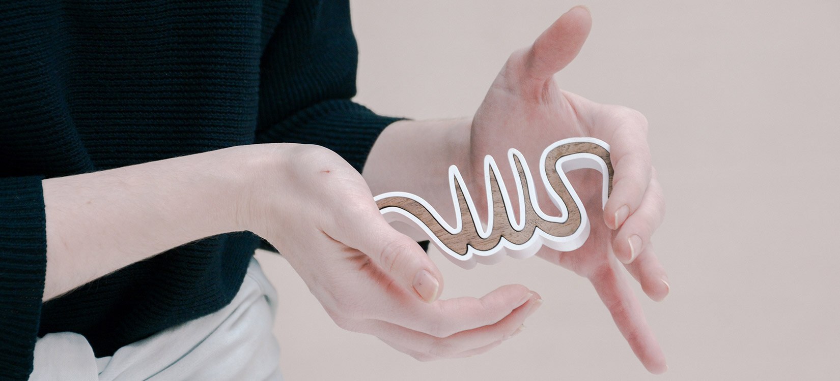 Nærbilde av hender som holder frem en treklosse i en buende form