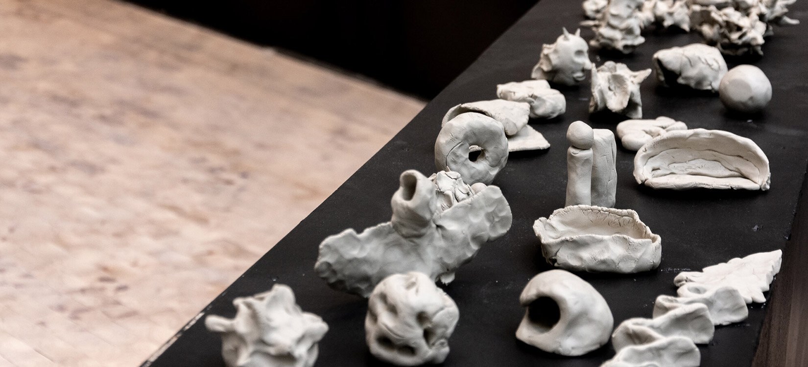 Et bord med en rekke abstrakte leirefigurer