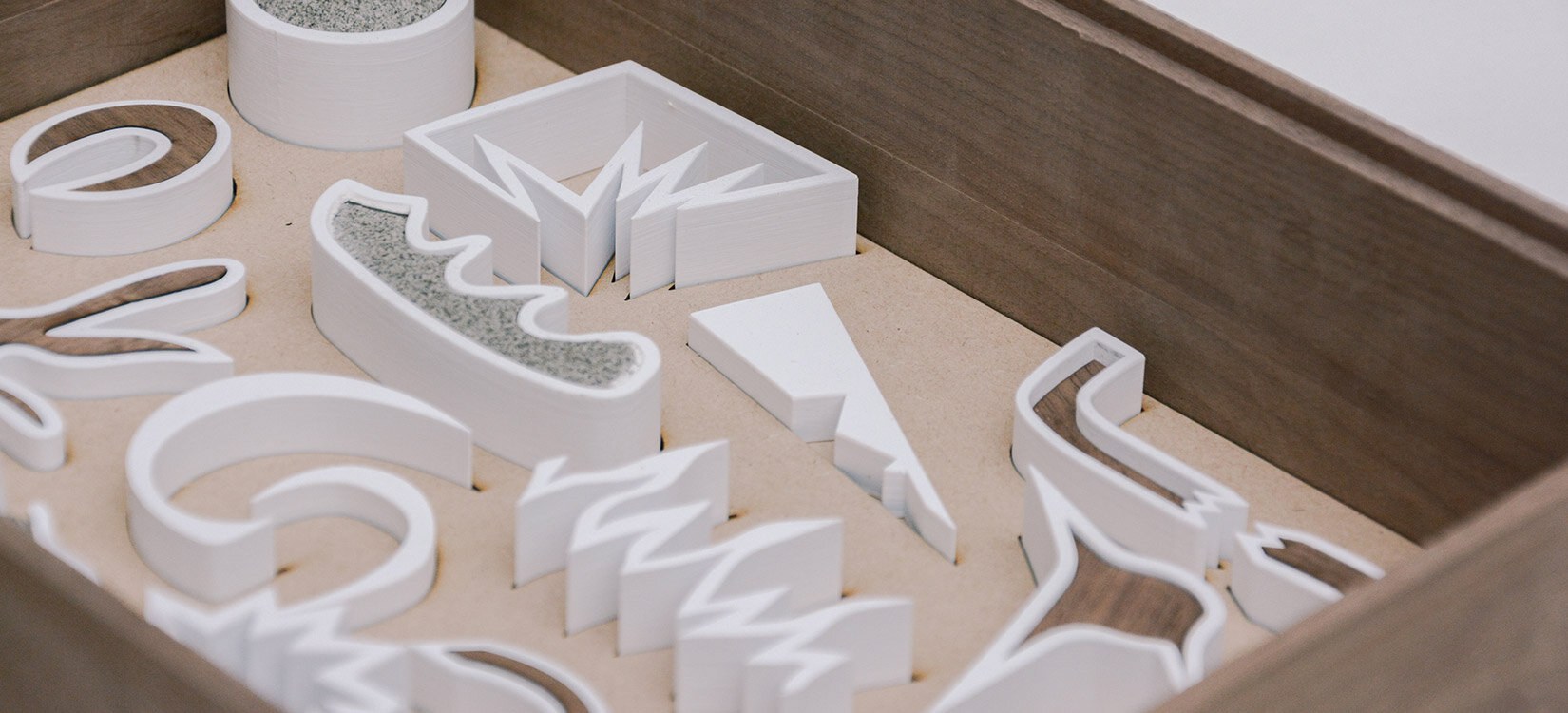 En serie figurer i abstrakte former ligger i en trekasse