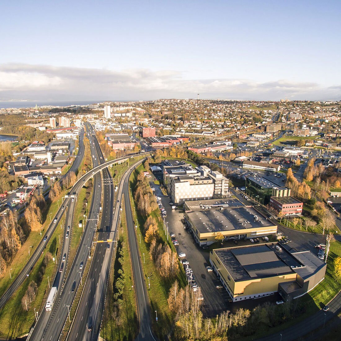Et flyfoto av et urbant byområde med en næringstomt og veinett nærmest kamera.