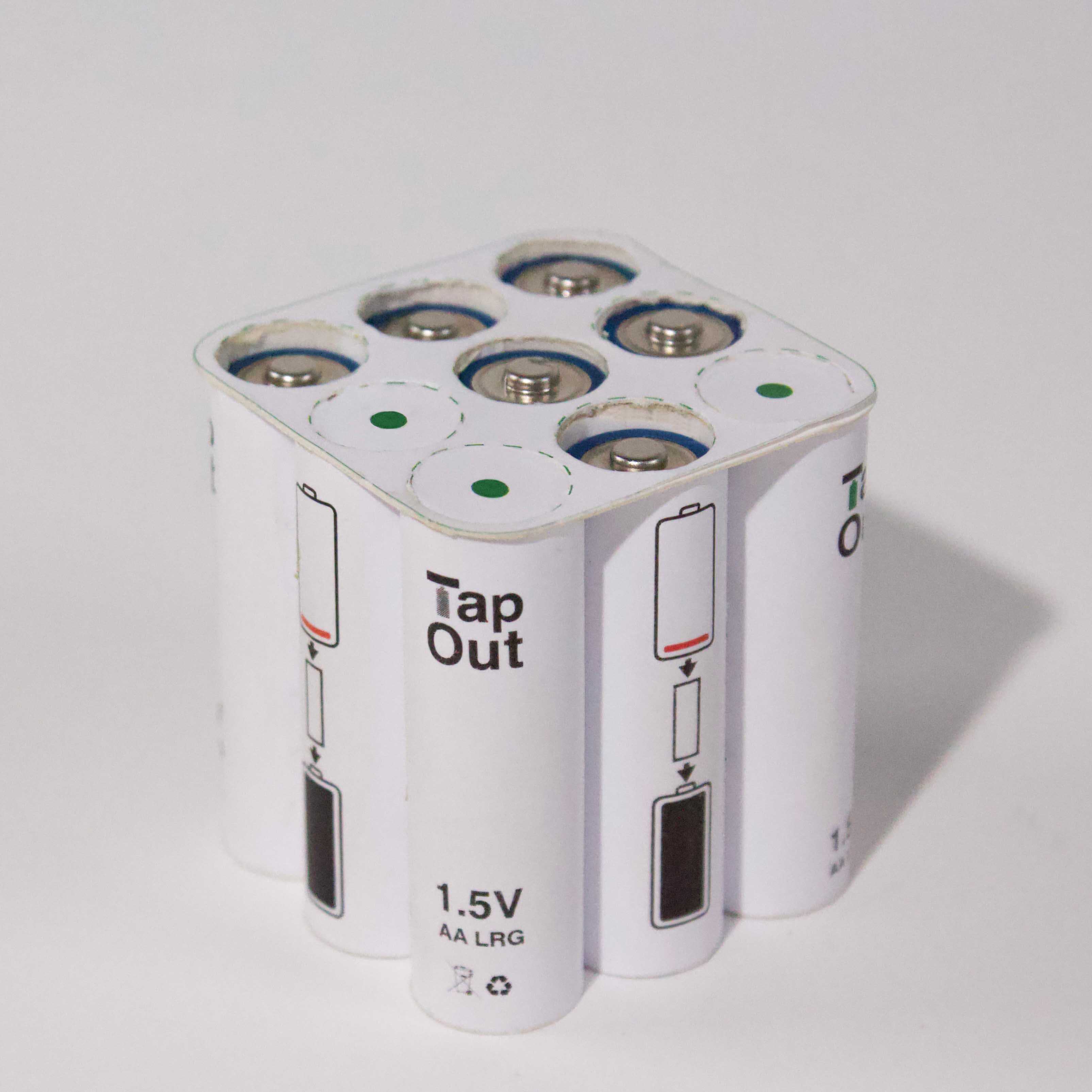 En liten hvit beholder for batterier. På toppen er det markert med grønne prikker og stiplede sirkler hvor batteriene er.