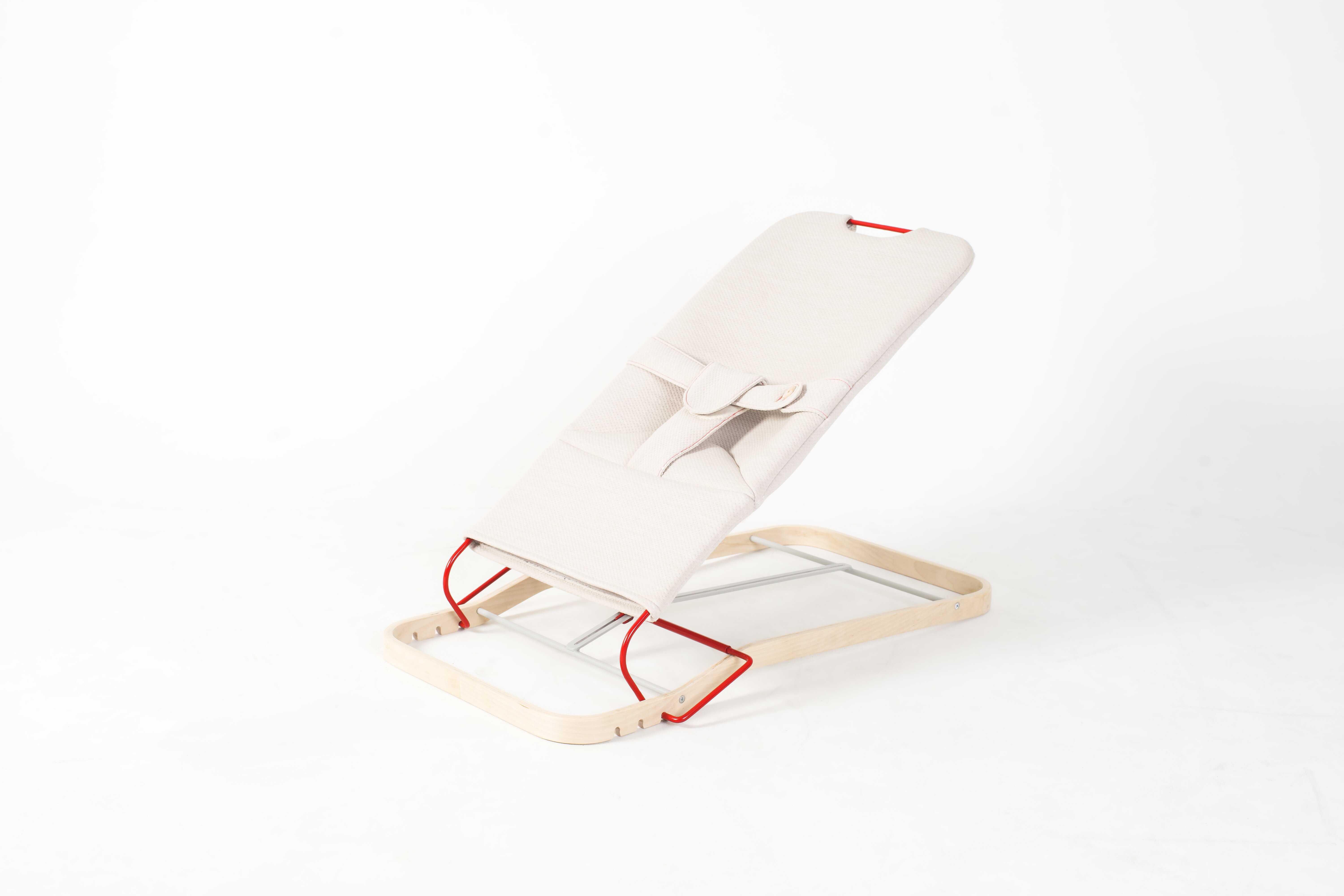 Bildet viser en vippestol. Stolen har stativ i naturlig treverk, lyst tekstil og ramme og detaljer i rødt metall.