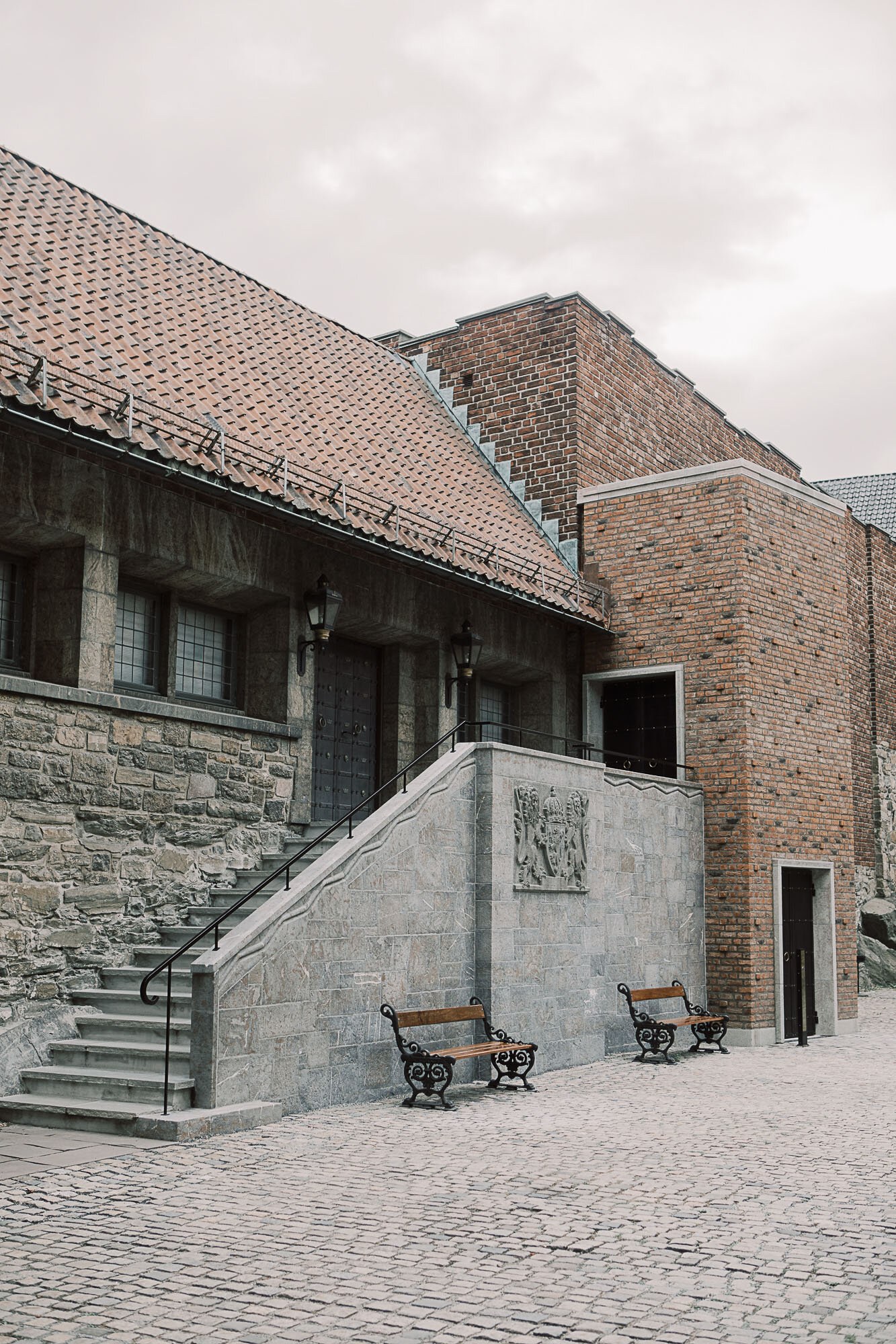 Akershus slott med steinfasade med trapp og rekkverk opp til inngang, og dør ved siden av i murveggen.