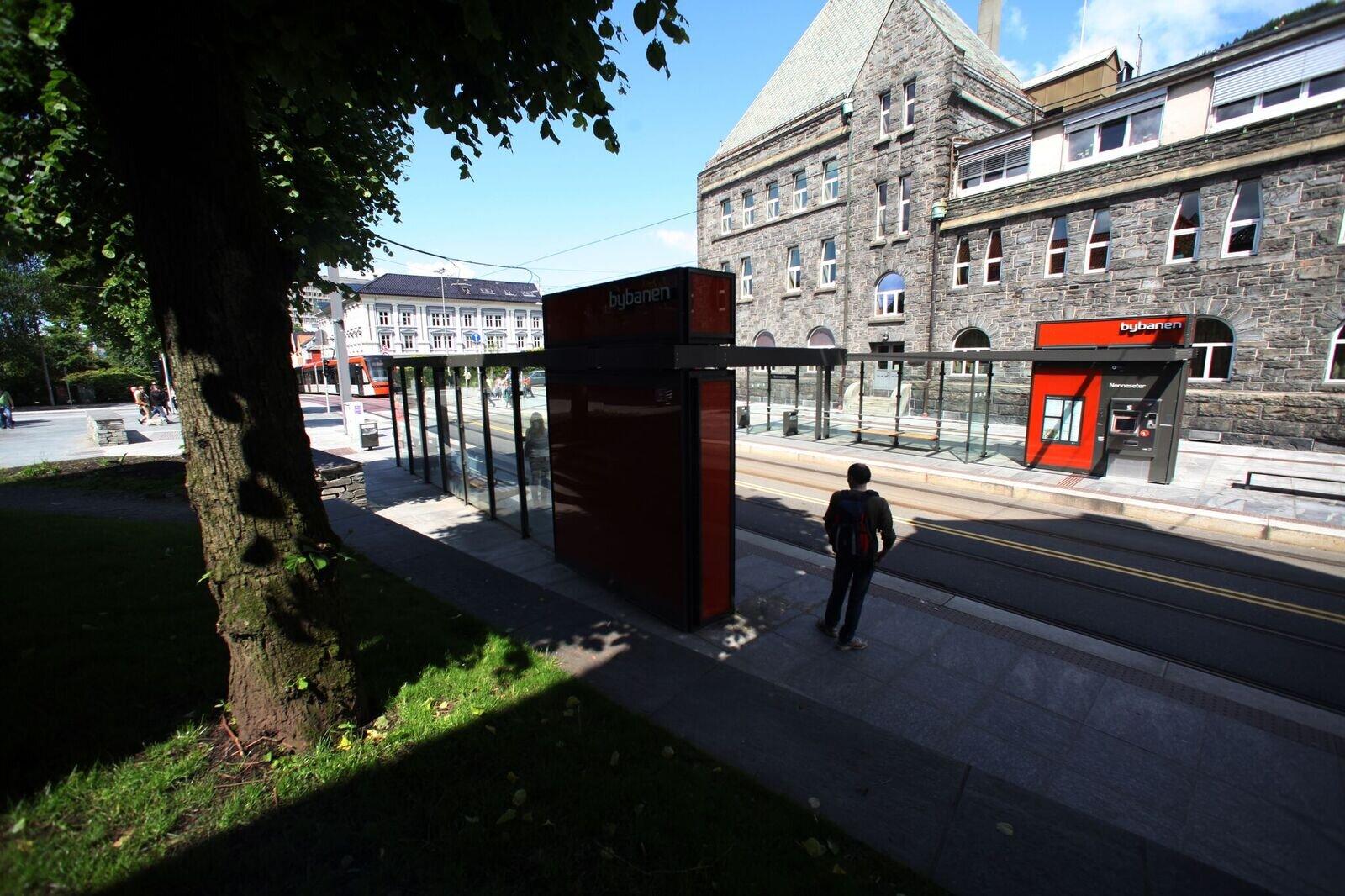 Bybanestoppet Nonneseter ved Bergen jernbanestasjon – men signaturfargede oransje elementer og overbygget venteareal.