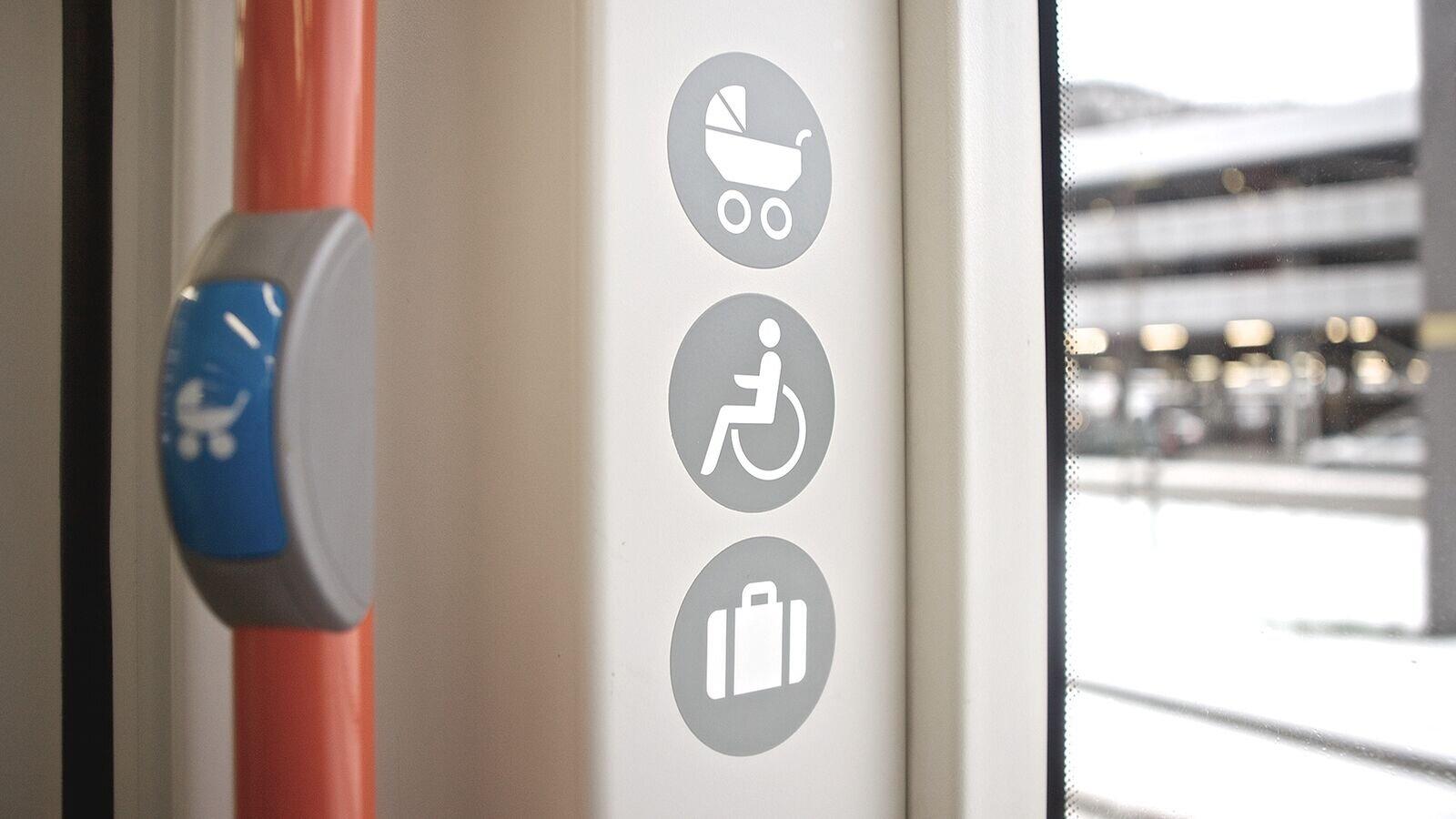 Nærbilde av runde symboler for barnevogn, rullestol og bagasje.
en blå stoppknapp med barnevognsymbol ses i forgrunnen.