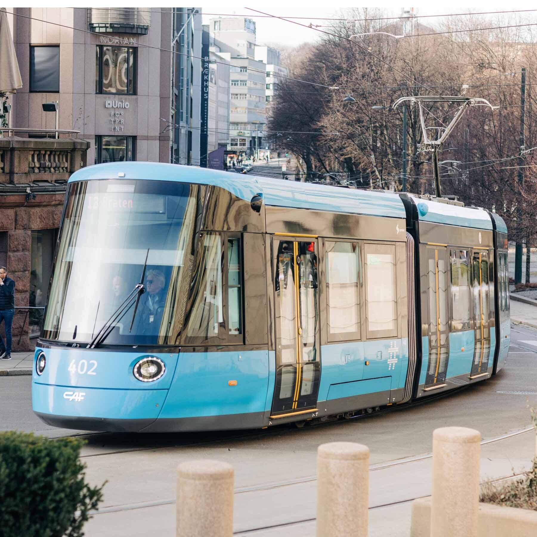 En blå trikk som svinger oppover en gate