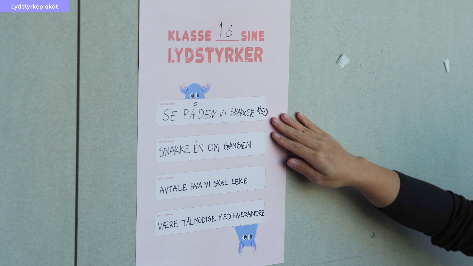 Hvit plakat med 1Bs lydstyrker skrevet på.
