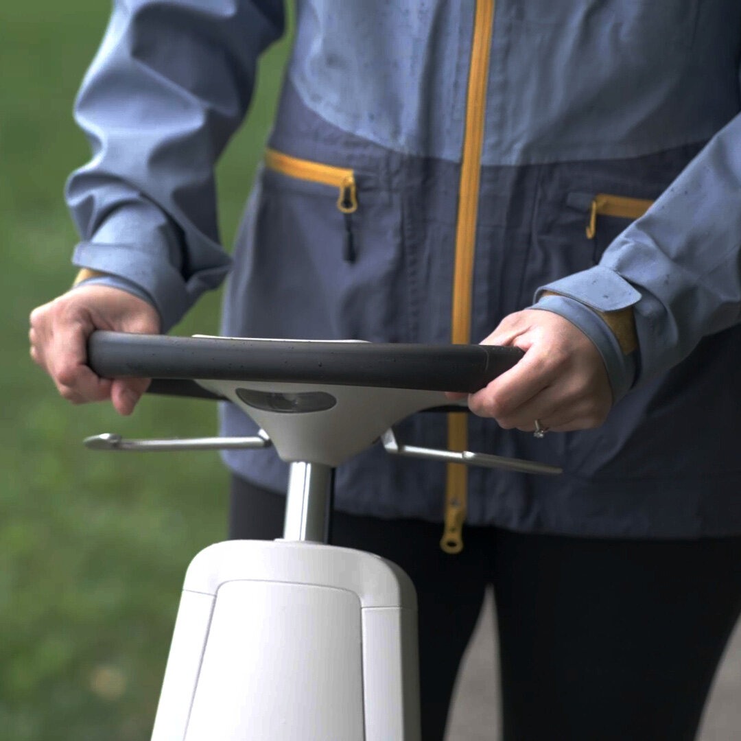 Nærbilde av styret på en trehjuling. To hender holder i styret.