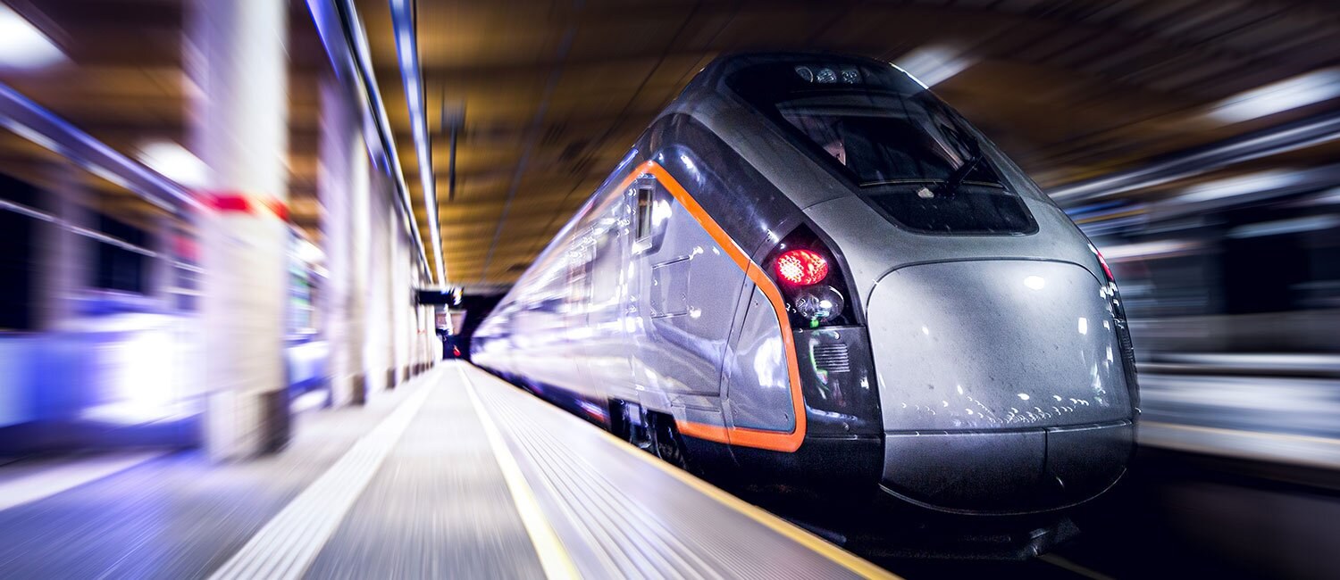 Flytoget ved en underjordisk perrong. Omgivelsene rundt toget er uskarpt, og indikerer at toget er i fart.