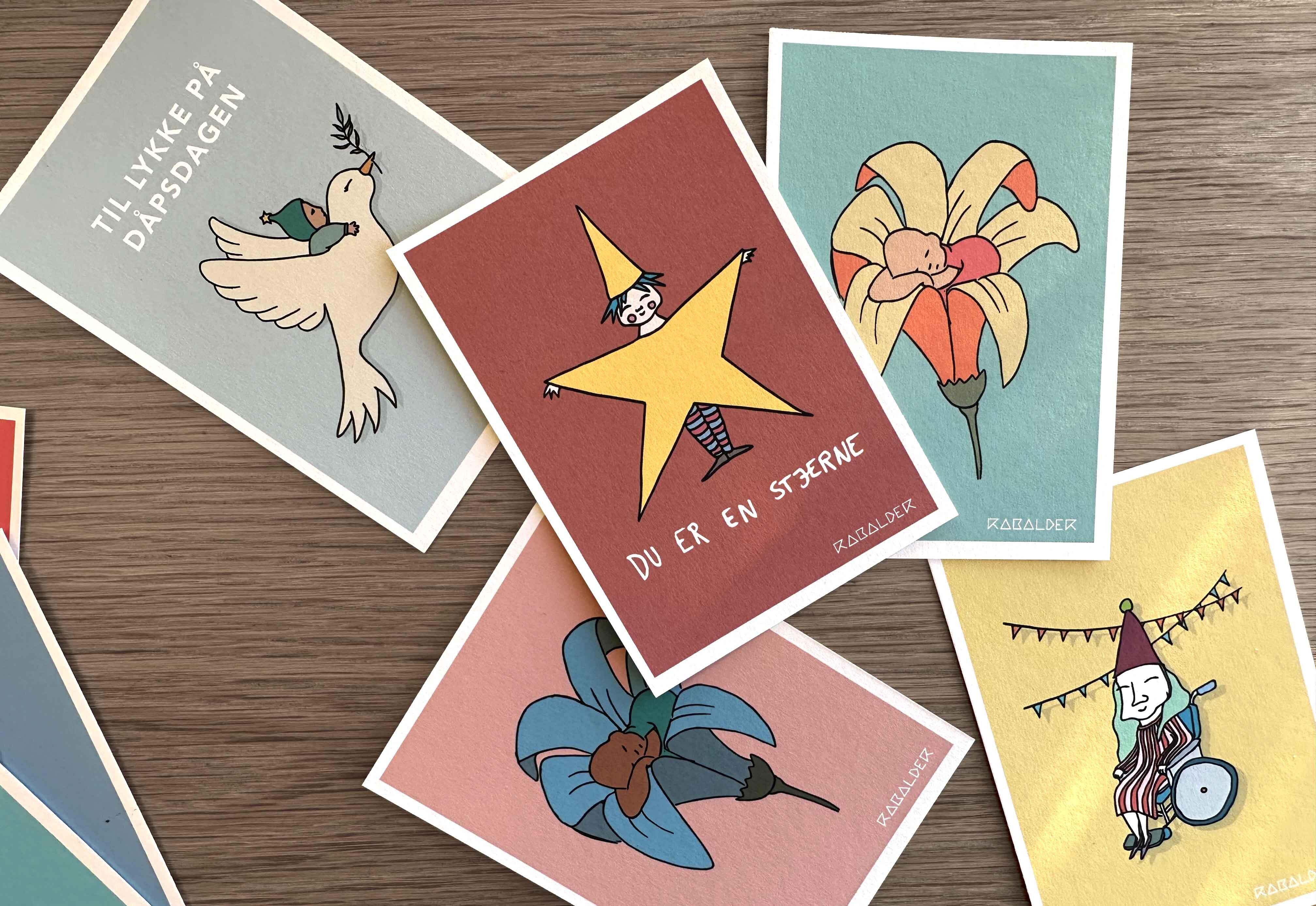 Samling med illustrerte gratulasjonskort på et bord.