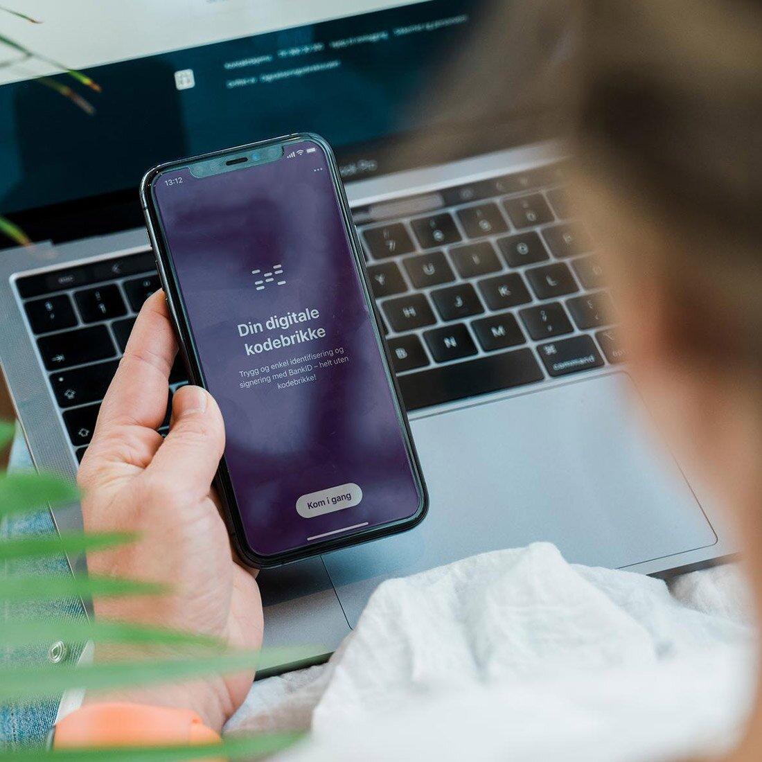 En person holder en smarttelefon med bankid-appen åpen.