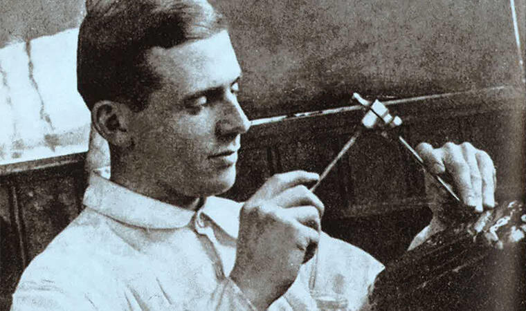 Eldre svart/hvitt fotografi av en ung mann som arbeider med en liten hammer og meisel.