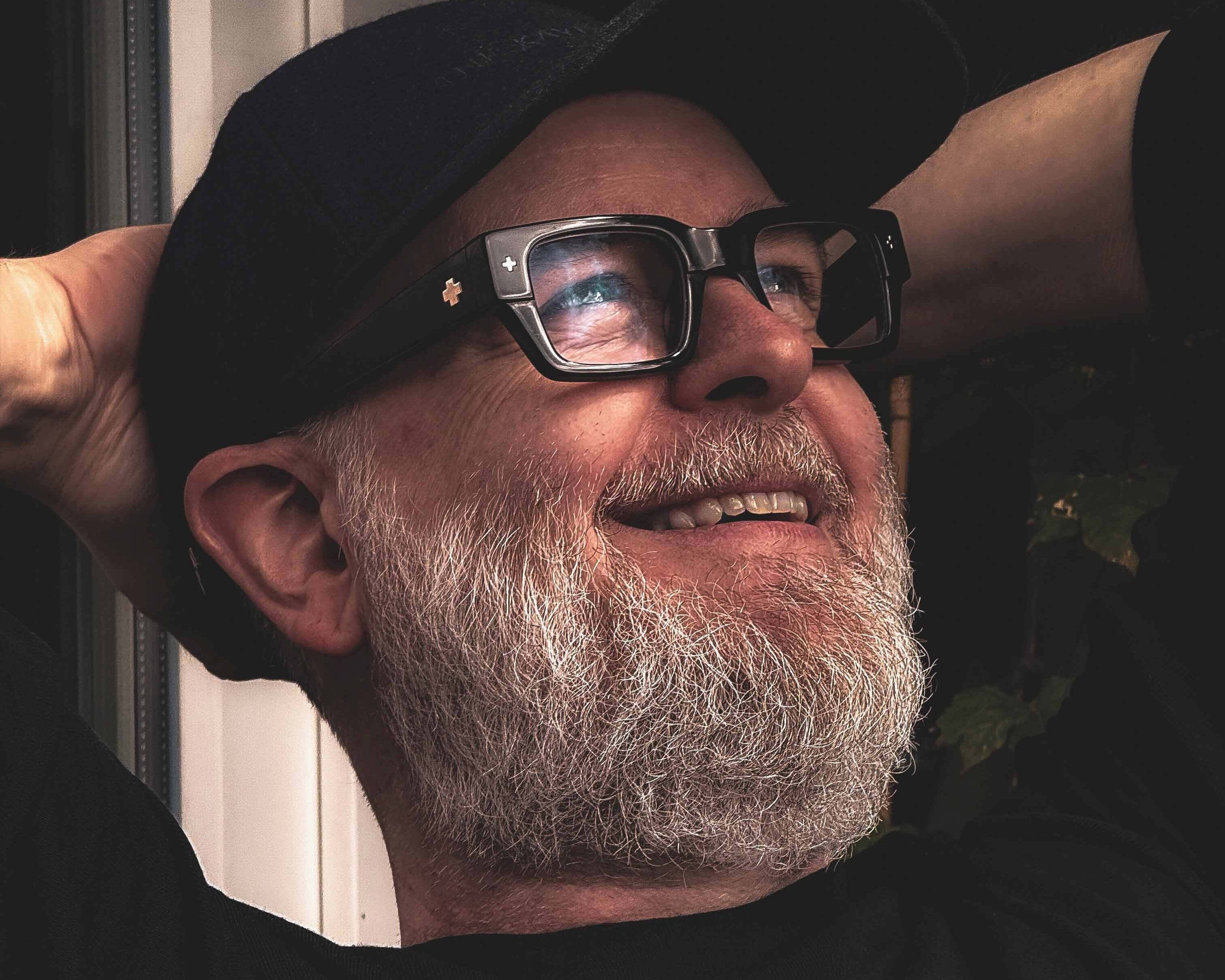 Foto av Magnus Rakeng som lener seg smilende tilbake.