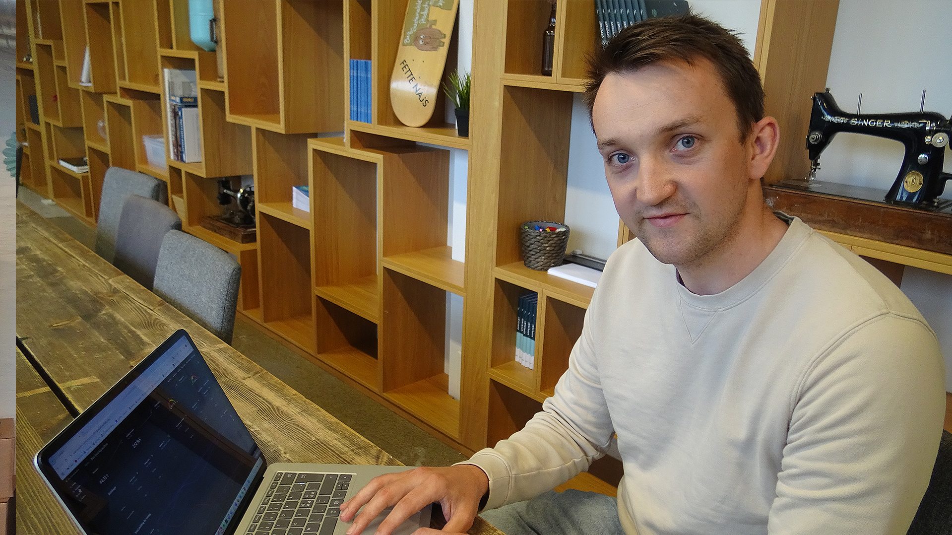 Foto av en mann som sitter ved en mac med én hånd på tastaturet.