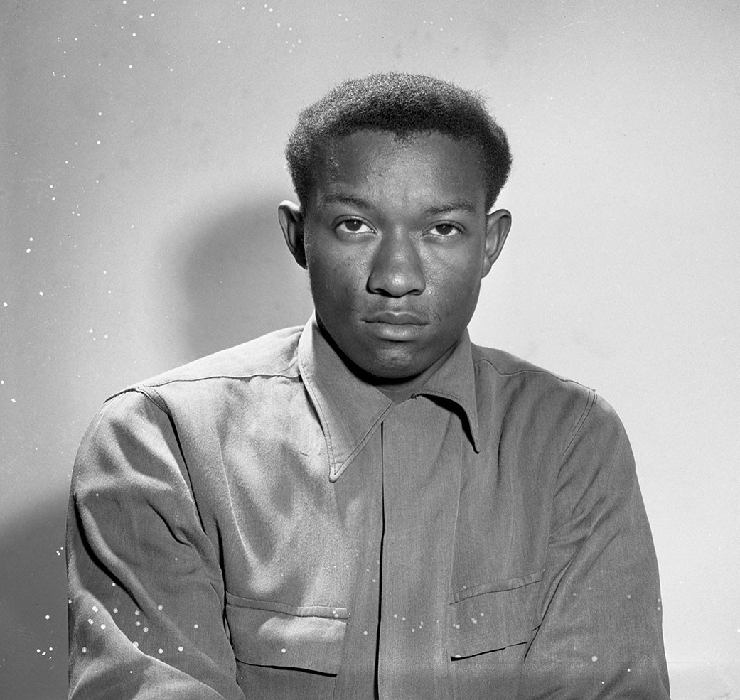 Tommy Lee Walker, a young Black man with short hair wearing a button-down shirt looking somberly at the camera