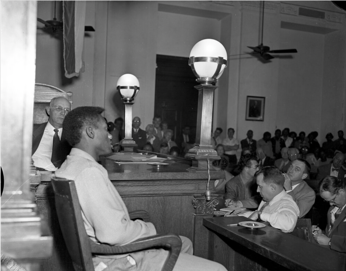 Tommy Lee Walker, a young Black man, sits in a chair facing a courtroom full of a mostly white crowd. An elderly white judge looks on.