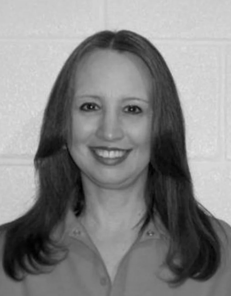 White woman smiling with brown hair, pictured in B&W