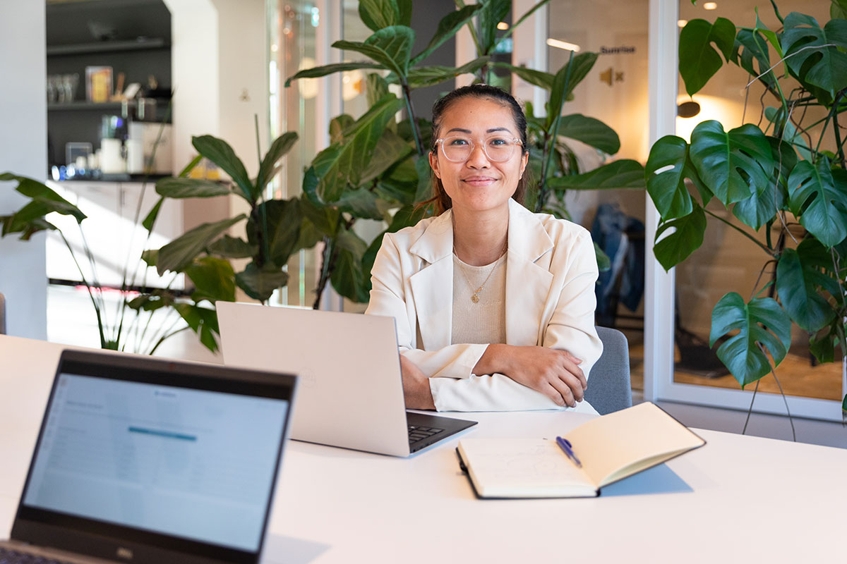 Kvinna i vit kavaj i en kontorsmiljö med dator framför sig